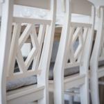 White chairs with gray cushions around a wooden table.
