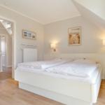 Bedroom with double bed, wall lamps, and view into the staircase.