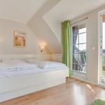 Bedroom with double bed, balcony, and green curtains.