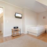 Room with two beds, TV, and wooden floor