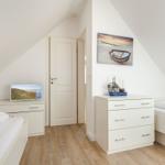 Room with two beds, dresser, and wall picture with boat.