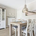 Dining room with table, chairs, and glass cabinet. Wall picture shows beach.