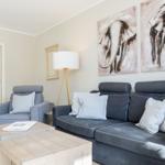 Living room with sofa, armchair, and wall art of elephants.