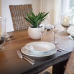 Wooden table with chairs, plates, glasses, and candles.