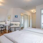 Bedroom with double bed, desk, and TV. Windows with view to balcony.