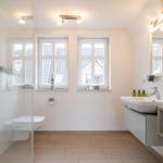 Bathroom with shower, toilet, sink, and windows.