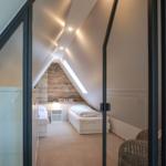 Room with two beds, sloped ceiling, and glass wall