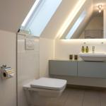 Bathroom with shower, sink and toilet under sloped ceiling.