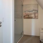 Shower area with glass enclosure, seagull artwork, and toilet cabinet.