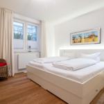 Bedroom with double bed, wicker chair, and window view.