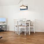 Wohnzimmer mit Essbereich, Fernseher und Küchenzeile.