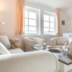 Wohnzimmer mit Sofa, zwei Sesseln, Tisch und Fenstern.