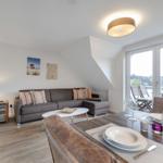 Living and dining area with sofa, table, and balcony view.