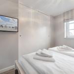 Bedroom with bed, window, and wall picture. White bedding and towels.