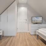 Room with two beds, wardrobe, and TV on dresser.