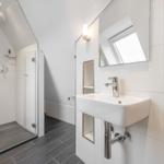 Bathroom with shower, sink, and shelves with towels and toiletries.