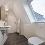 Bathroom with shower, sink and toilet under sloped roof