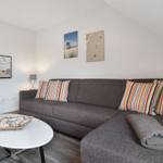 A living room with a gray sofa, colorful cushions, and a round table.