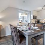 Dining room with table, chairs, and kitchen. Attic with window and lamp.
