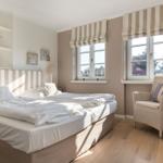 Bedroom with double bed, two windows, and chair.