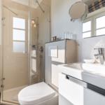 Bathroom with shower, sink, and toilet. Windows provide natural light.