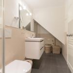 Bathroom with sink, mirror and shower under sloped ceiling