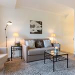 Living room with sofa, armchair, table, and wall art.