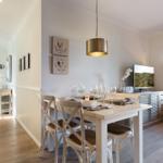 Dining room with table, chairs, and TV. Window with roller blind and wall art.