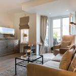Living room with sofa, armchair, TV, and window to terrace.