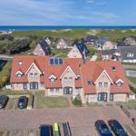 Haus mit rotem Dach und Solaranlage, Blick auf Meer und Grünflächen.