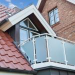 Dachgeschoss balkon mit glasgeländer und rotem dachziegel