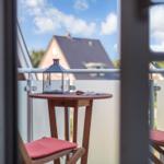 Balkon mit Tisch, Laterne und zwei Stühlen mit roten Sitzkissen.
