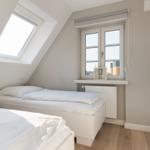 Zimmer mit zwei Betten, Dachfenster und Fenster mit Blick.