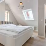 Schlafzimmer mit Dachschräge, Doppelschreibtisch und Fenster. Nebenraum mit Toilette und Dachfenster.