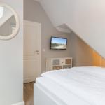 Schlafzimmer mit Dachschrägen, Bett, TV und Spiegel an der Wand.