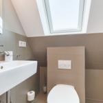 Badezimmer mit Waschbecken, Toilette und Dachfenster.