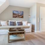 Wohnzimmer mit Sofa, Couchtisch und Wandbild unter Dachschrägen.