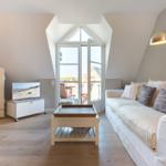 Wohnzimmer mit Sofa, Kühlschrank und Balkontür.