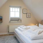 Bedroom with sloped ceiling, bed, window, and wall art.