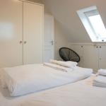 Bedroom with sloped ceiling, skylight, and white bed.