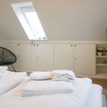 Bedroom with sloped ceiling, skylight, bed, and TV.
