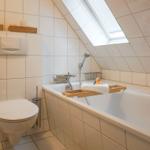Bathroom with bathtub, shower, and toilet under sloped ceilings