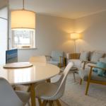 Dining area with round table and chairs. Living area with sofa and armchairs.