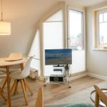 Living and dining area with TV, table and chairs, and windows.