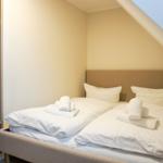 Bedroom with double bed, pillows, and folded towels under sloped ceiling.