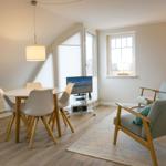 Dining area with table, chairs, and TV. Two armchairs on rug.