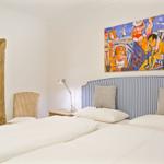 Schlafzimmer mit Bett, Wandbild und Spiegel mit rustikalem Rahmen.
