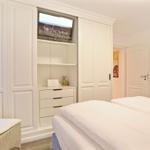 Schlafzimmer mit weißem Bett, Kleiderschrank und Fernseher.