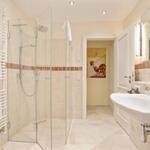 Badezimmer mit Dusche, Waschbecken und Heizkörper mit Handtüchern.