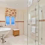 Badezimmer mit Dusche, Waschbecken und Fenster mit Meerblick.